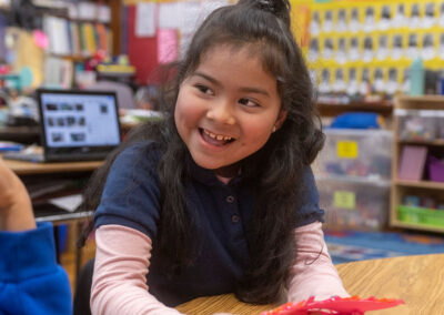 A child in a classroom, smiling.