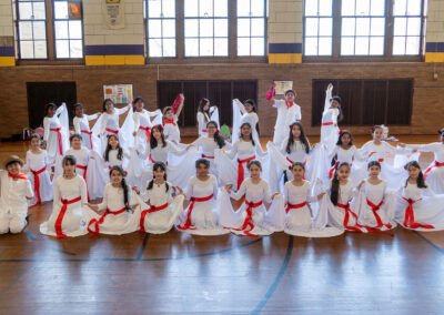 A group of children in matching white outfits.