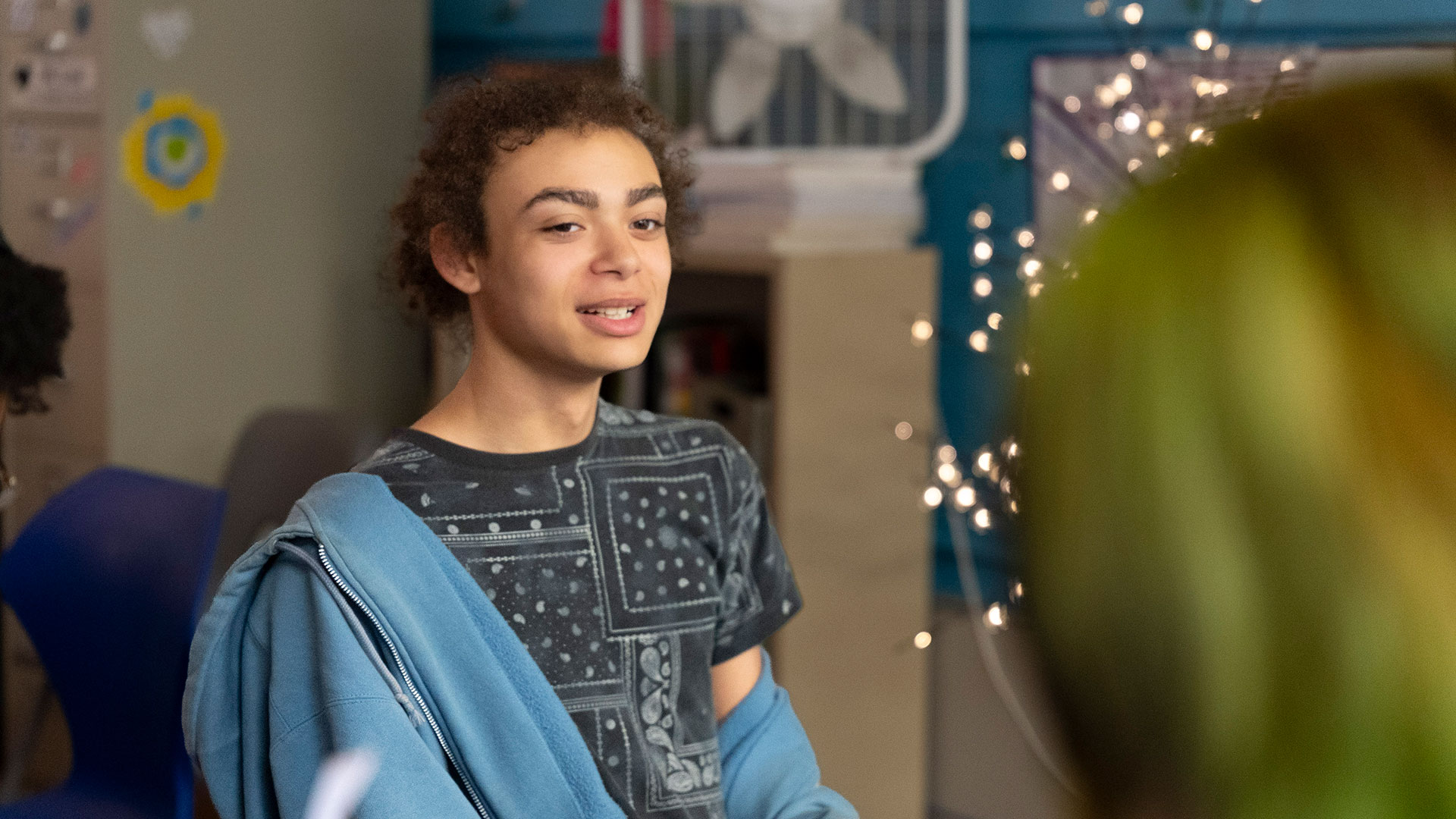 A boy in a classroom talks to another student.