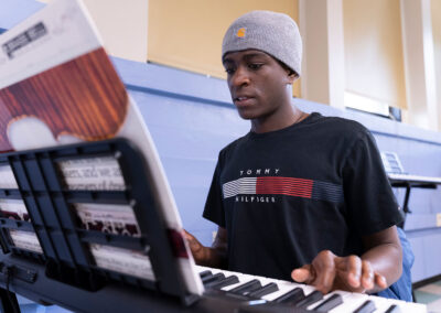 A boy in a classroom playing the keyboard.