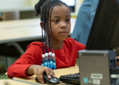 A girl concentrates as she uses a computer.