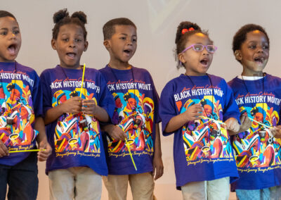 Young students with matching Black History Month shirts, singing.