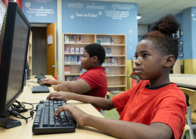 Two students in a classroom using computers.