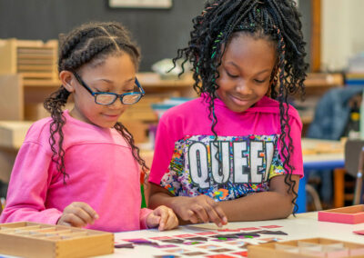 Two girls in a classroom working together on a project.