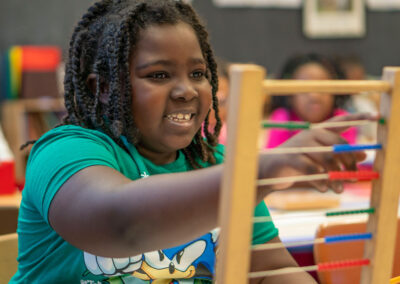 A girl smiles while moving a bead on an abacus.