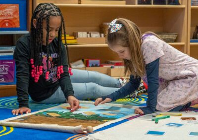 Two young students work on a project while on the floor.