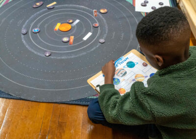 A boy sits on the floor and learns the solar system.