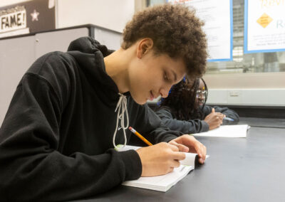 Students at a table writing in a workbook.