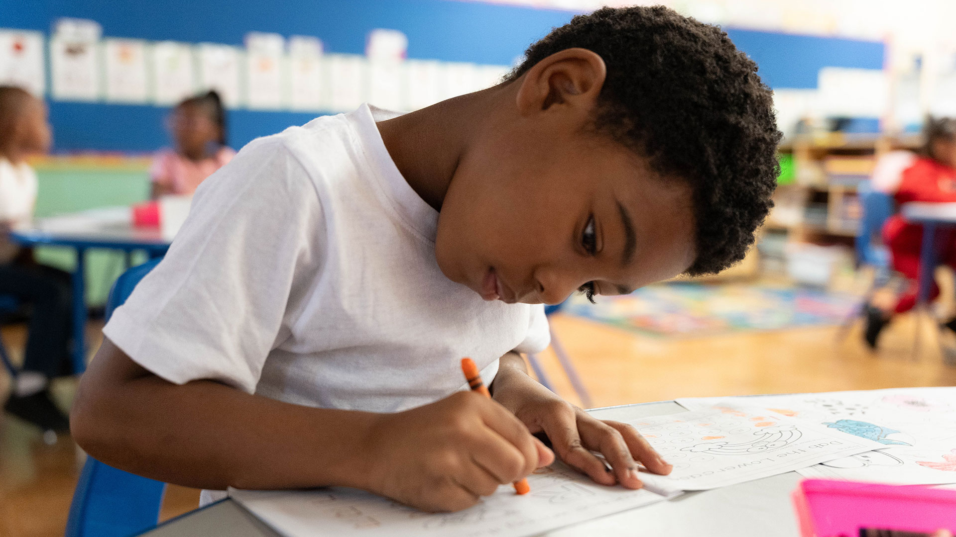 A young student in a classroom coloring.