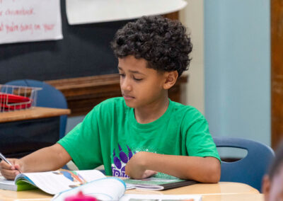 A child at a desk writing in a workbook.