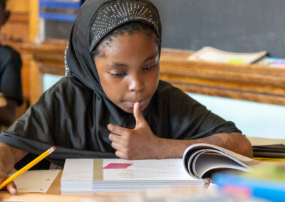 A young child at a desk, concentrating on her school work.
