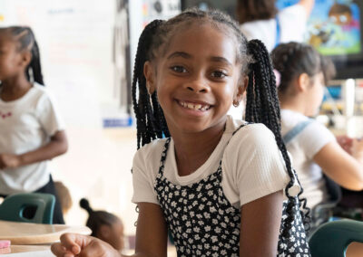 A child in a classroom smiling.