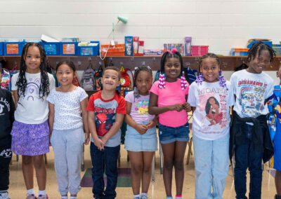 A line of young children in a classroom smiling.