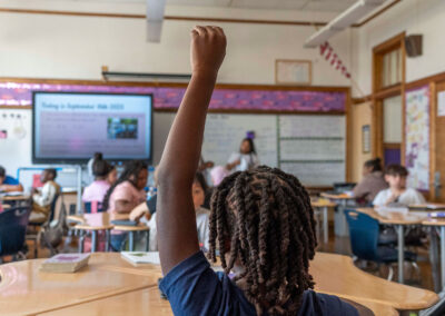 A student in a classroom raises his hand.