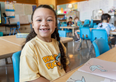 A young child smiles while reading a book.
