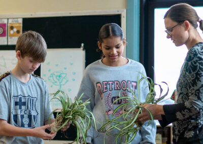 Students and their teacher look at the roots on plants.