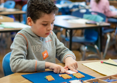 A student at t table using beads to count.