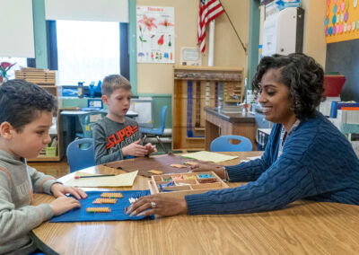 A teacher and her two young students use strings of beads to count.