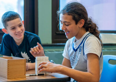 Two boys smile as they stack small blocks.