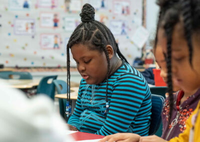 Young students in a classroom looking down at their schoolwork.