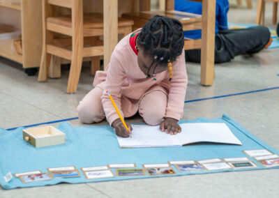 A young girl on the floor writing in a notebook.