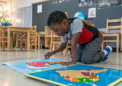 A boy on the floor putting a puzzle of South America together.