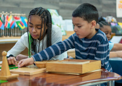 Two students putting pegs into a board.