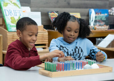 Two students with a tray of colorful beads in test tubes.