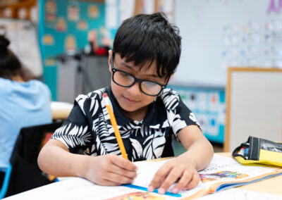 A student in a classroom writing in a workbook.