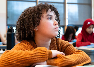 A child in a classroom looking to the front of the class.