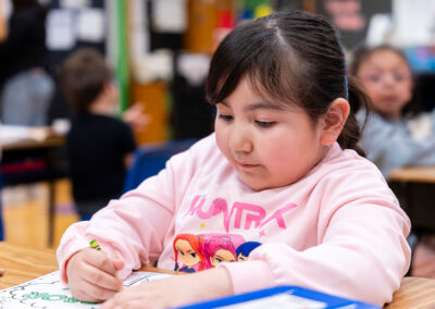 A young child in a classroom coloring.