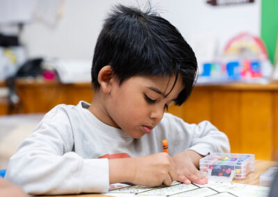 A young child at a table coloring.