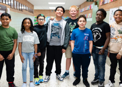 A group of students stand in a school hallway.