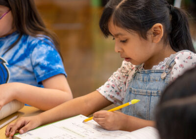 A young girl writes in a workbook.