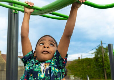 A boy hanging from monkey bars.