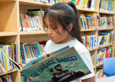 A child in a library, looking at a picture book.