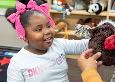 A young child smiles with a plush turkey.