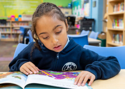 A child in a library, looking at a picture book.