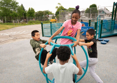 Young children spin on playground equipment.