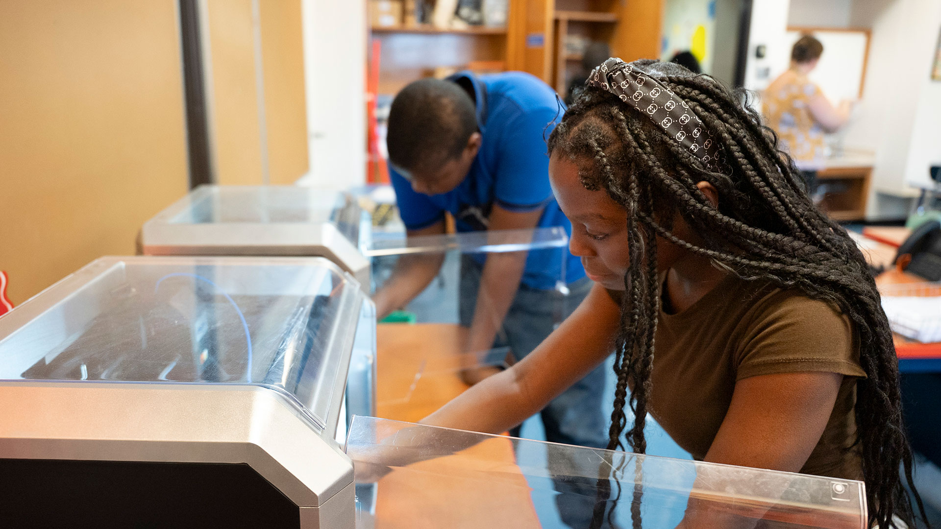 Two students look inside 3D printers.