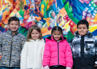 Cov menyuam yaus hnav tsho tiv no lub caij ntuj no nyob rau pem hauv ntej ntawm daim duab kos duab muaj yeeb yuj.