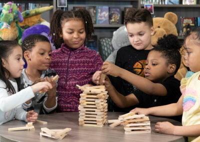 A group of young children at a table playing Jenga.