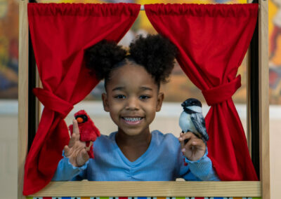 A young girl puts on a puppet show with bird finger puppets.