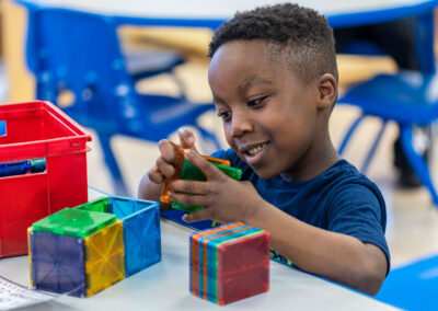 A young boy playing with magnetic tiles.