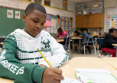 A boy in a Milwaukee Bucks sweatshirt filling out a worksheet.