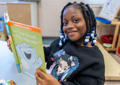 A smiling girl reading a book.