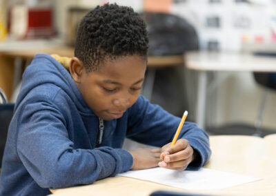 A boy at a desk, writing.