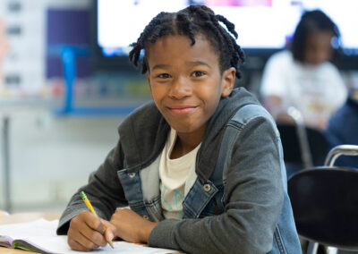 A boy smiles as he works on an assignment.