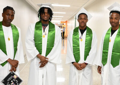 Graduates in caps and gowns wait in a hallway.