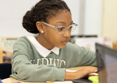 A girl concentrates as she types on the computer.